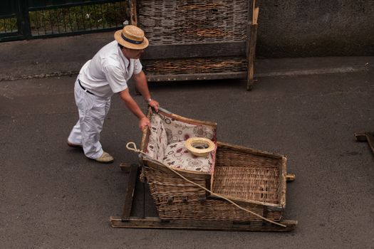 Traditional toboggan man operating a wicker basket car.