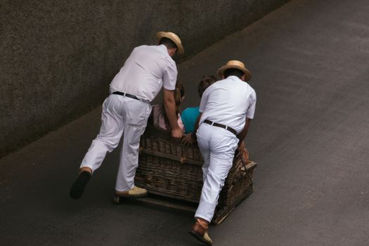 Traditional toboggan men operating a wicker basket car.