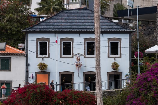 Typical house on Madeira island with black rooftop tiles and flower vases.
