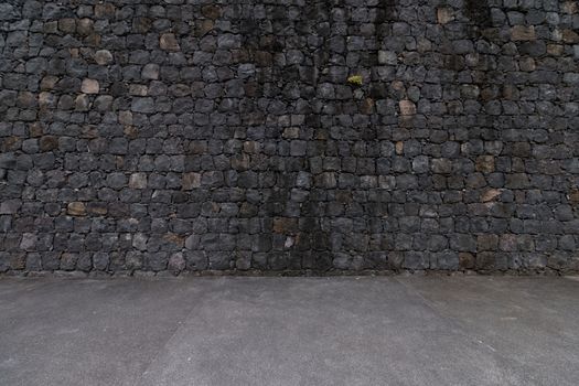 View of a dark stone wall background with ground.