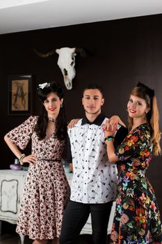 Two woman and a man posing on a vintage style retro clothing.