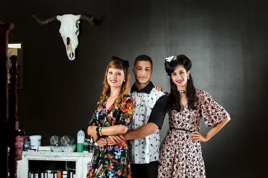 Two woman and a man posing on a vintage style retro clothing.