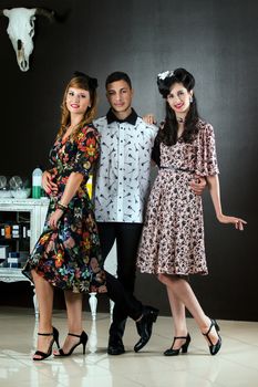 Two woman and a man posing on a vintage style retro clothing.