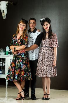 Two woman and a man posing on a vintage style retro clothing.