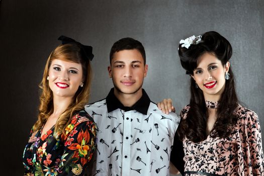Two woman and a man posing on a vintage style retro clothing.