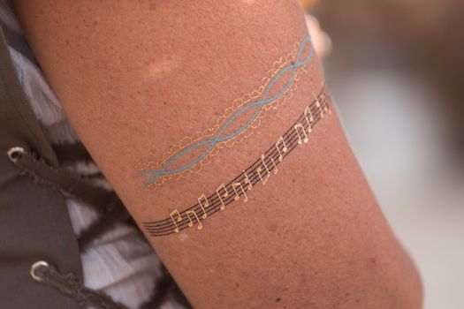 Close up view of a golden music tattoo in a arm.