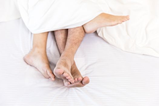 young sexy couples in love lying in bed in hotel, embracing on white sheets, close up legs, romantic mood