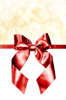 Red gift ribbon bow and golden bokeh isolated on white background