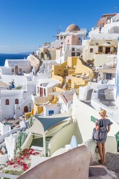 Female tourist enjoying beautiful wiev of world famous Oia village or Ia at sunset, Santorini island, Greece.