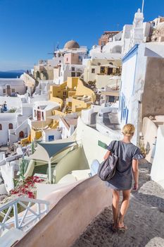 Female tourist enjoying beautiful wiev of world famous Oia village or Ia at sunset, Santorini island, Greece.