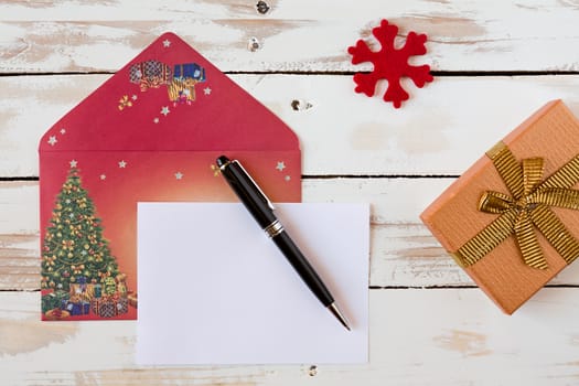 Christmas letter and pen over a rustic wooden table with present