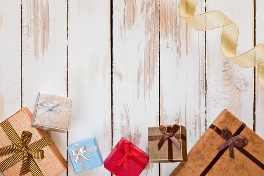Christmas presents and golden ribbon over a rustic wooden table seen from above