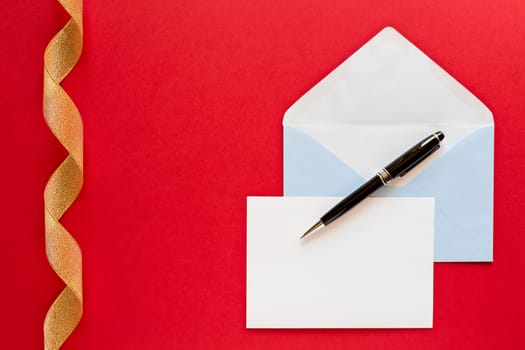 Christmas letter and pen over a red background with golden ribbon
