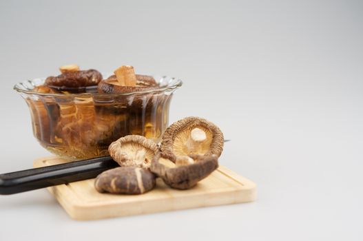 Shitake mushroom and soak mushroom in bowl and knife place on chopping board with white background and copy space.