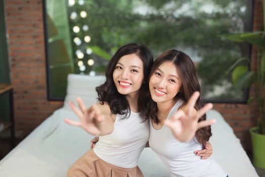 Two asian women in the bedroom on the bed have fun