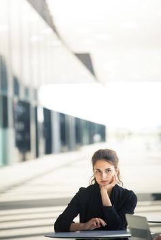 Thoughtful business woman sitting in cafe of modern office building