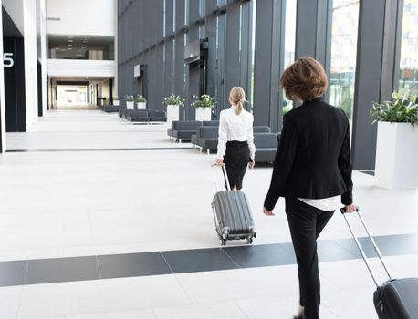 Business people in formal clothing walking in airport terminal with suitcases