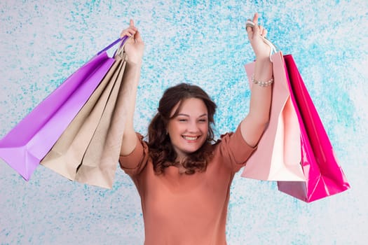 Happy smiling woman at shopping holding colourful paper bags in both hands