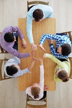 Coworkers doing high five sitting at the office table, top view