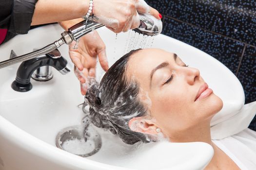 White woman getting a hair wash procedure in a beauty salon