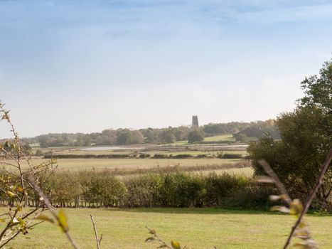 english church far off in the horizon beyond far fields outside blue sky; essex; england; uk