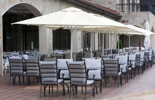 Restaurant tables, chairs and white umbrellas.