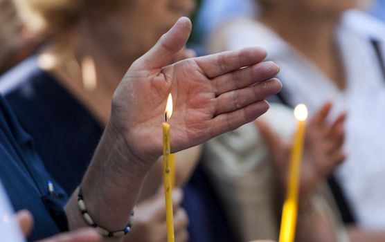 A hand shields a candle during a religious ceremony.