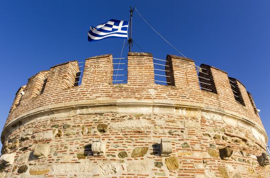 White Tower and Greek flag in Thessaloniki in Geece.