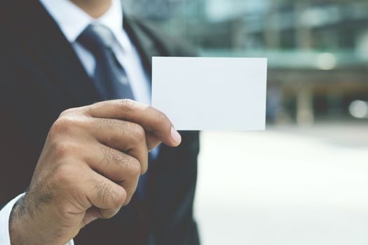 Young businessman who takes out blank business card from the pocket of his shirt business suit, copy space