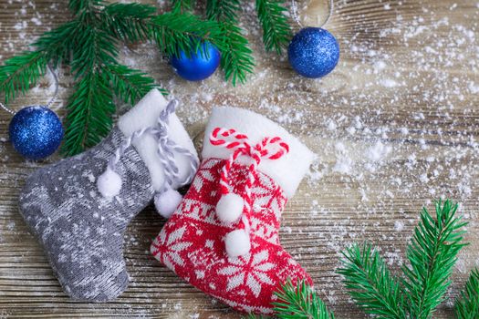 Christmas and New Year winter holiday snowbound composition of stockings on wooden space background with green fir tree branches and balls ornament