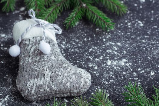 Christmas and New Year winter holiday snowbound composition of grey stocking on black space background with green fir tree branches