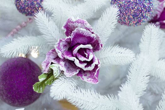 Christmas and New Year seasonal decoration on white fir tree with purple balls and flower ornament