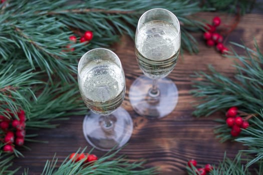Christmas and New Year seasonal composition with pine tree branches, two glasses of champaign and red rowan berries