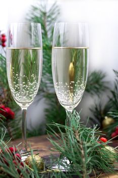 Christmas and New Year seasonal composition with pine tree branches, two glasses of champaign, golden balls ornament and red rowan berries