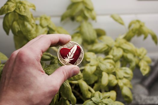 Digital currency physical gold metal feather coin with red heart. Cryptocurrency concept.