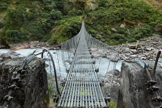 Suspension bridge over the rough mountain river in Nepal