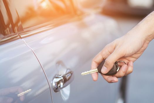 Cropped view of Closeup of a man's hand inserting key into the door lock of a car