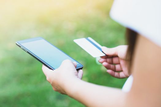 hands holding a credit card and using cell phone online shopping outdoor.