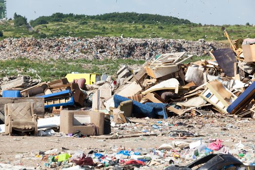 Old furniture at the garbage dump in focus, nature and blue sky in the background