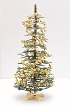 A small artificial Christmas tree decorated with decorative beads on a white background.
