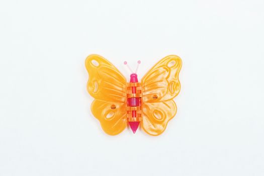 Little decorative butterfly made of plastic on a white background.