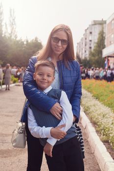 The first time in first class: happy schoolboy with his mother going to the school in first time