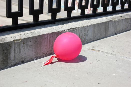 Pink ball on the concrete embankment with a metal fencing