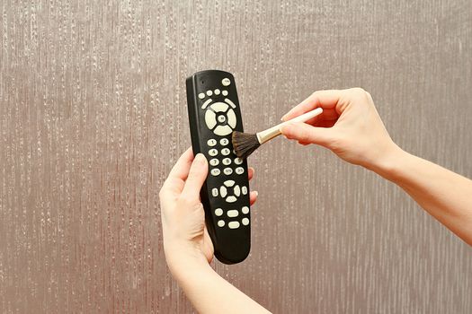 Cleaning brush dust of the remote control on a neutral background.