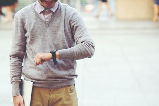 The young man holding tablet stand wait looking forward to watching the clock.