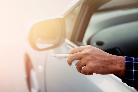 close up hand smoking a cigarette in car.