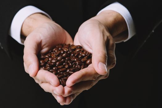 Coffee beans in hands on white background