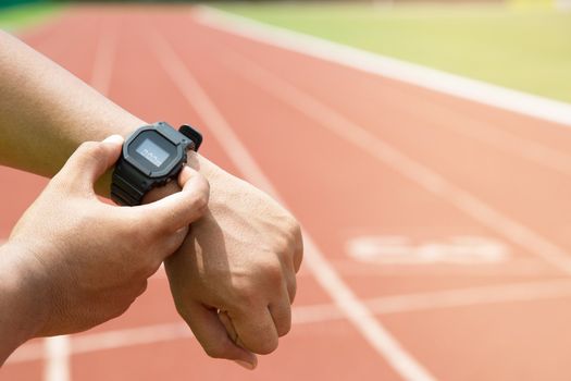 close up hands Athlete checking his watch Race timer runner ready to run on running track.