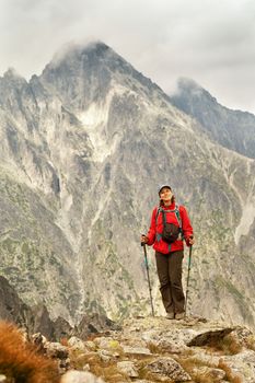 Happy woman with backpack standing on a rocky mountain background. Tatra Mountains, Slovakia, Europe