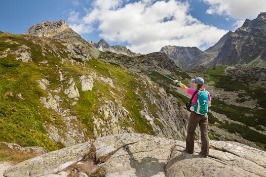 Happy woman with backpack standing and looking on high rocky peaks in Tatra Mountains, Slovakia, Europe